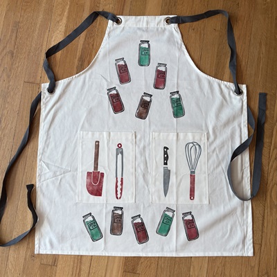 Handmade block print apron with cooking utensils on it.