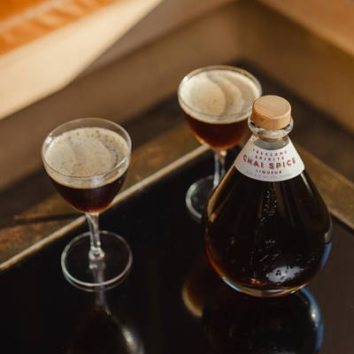 A bottle of Freeland's Chai Spice Liqueur with two glasses of chai-spresso martini's 