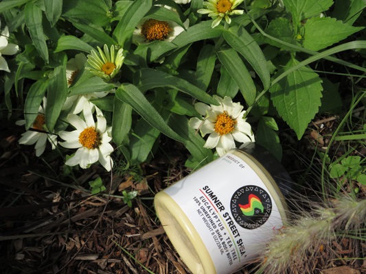 Jar of shea butter next to flowers