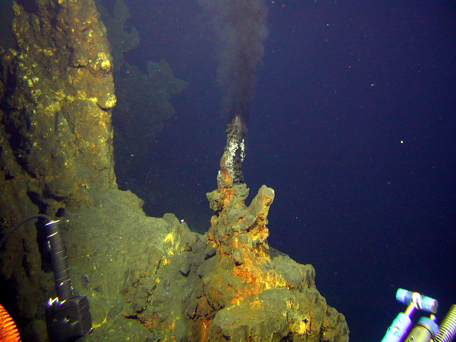 green and yellow rocks venting a cloud of dark gray liquid under the ocean