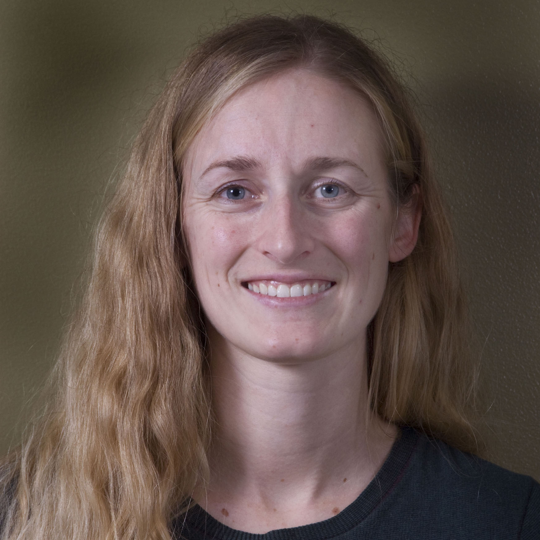 Alice smiling in front of neutral backdrop