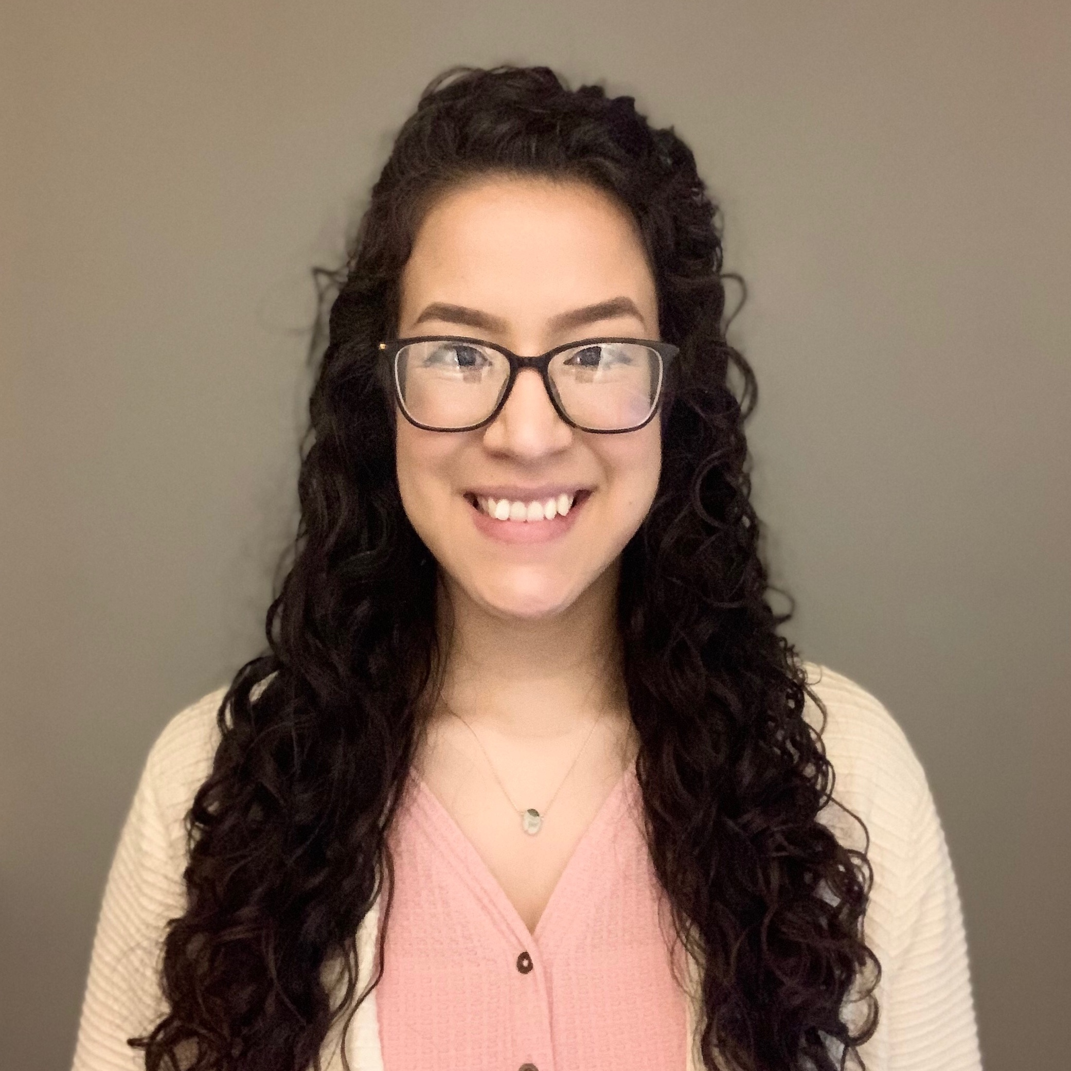 Ivanny smiling in front of neutral tan background