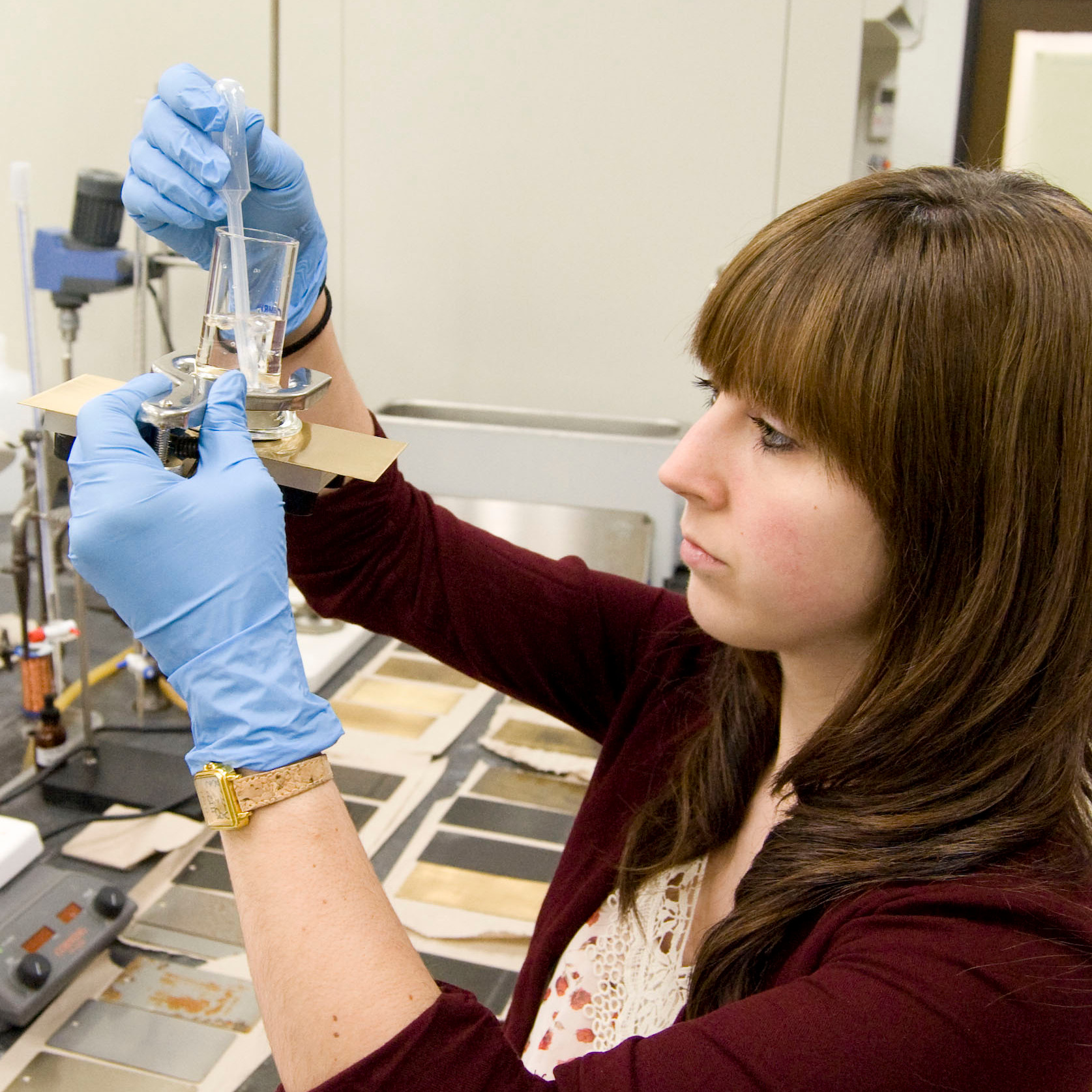Katy inspecting metal plate and beaker filled with fluid