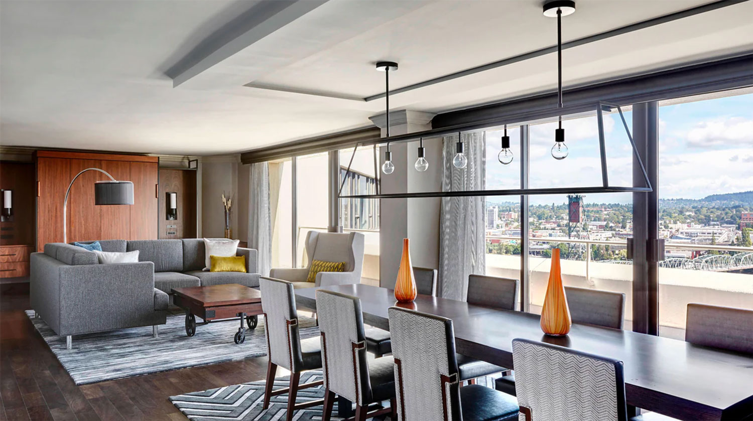 Couches, table and seating with a view of the riverfront in a suite at the Downtown Portland Marriott.