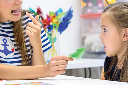 A woman works with a young girl on speech communications.