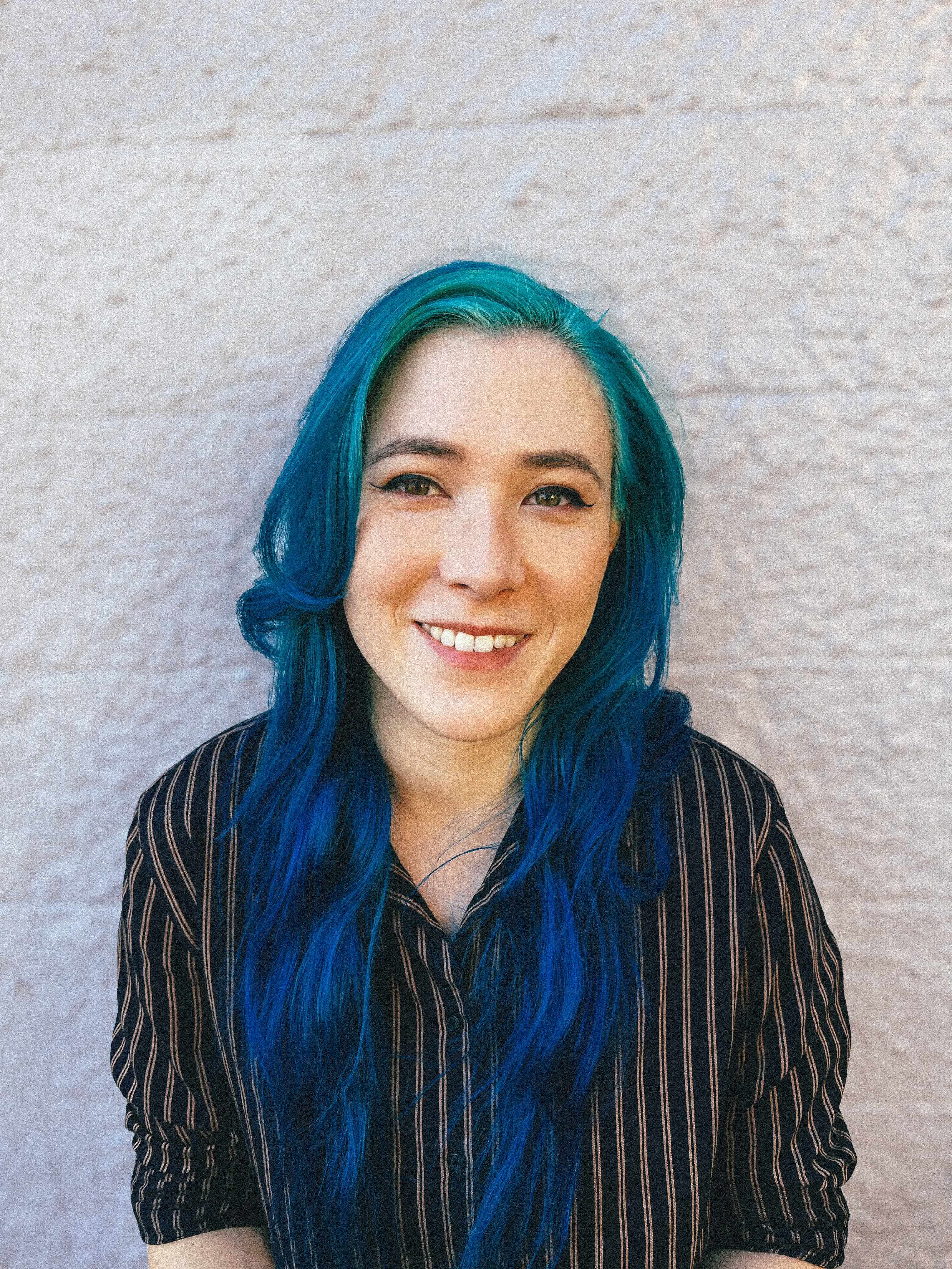 Picture of Maeve MacLysaght: woman with blue hair and wearing a striped black shirt