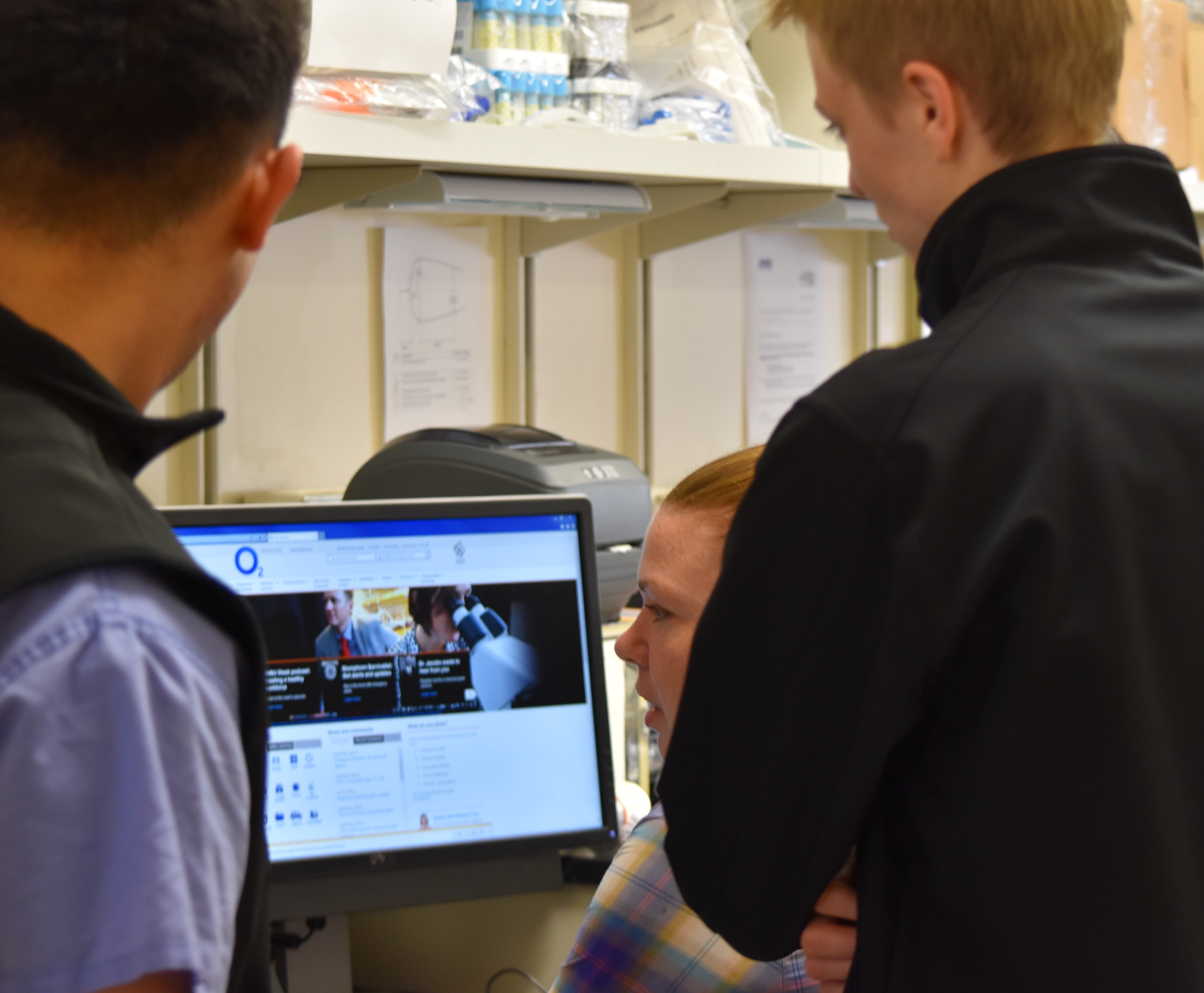 3 people look at a computer in a lab setting