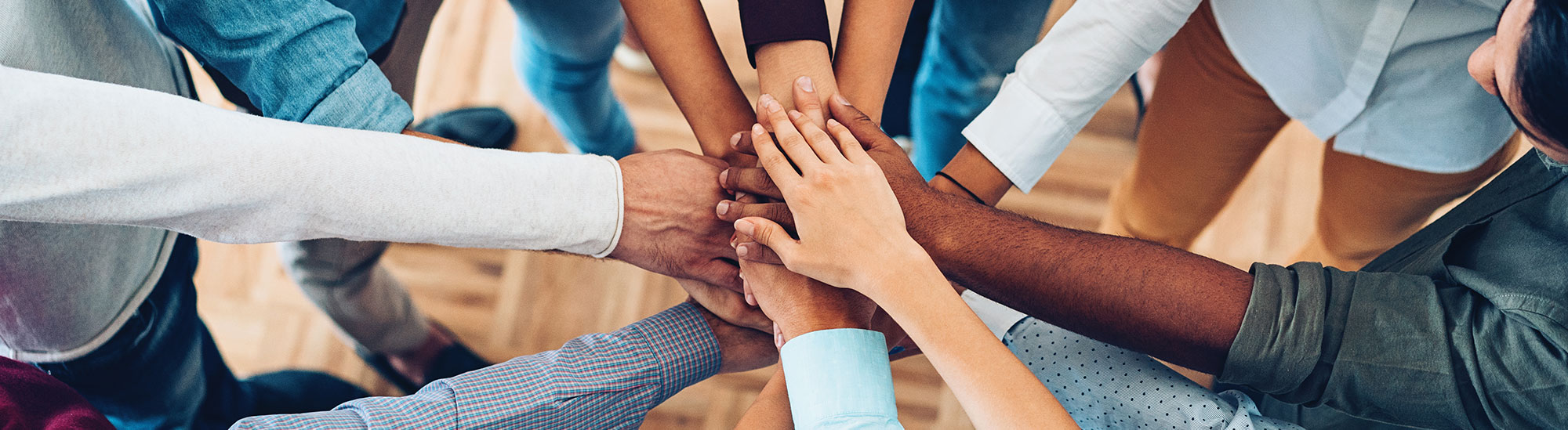 A group of people putting there hands in the center of a circle together