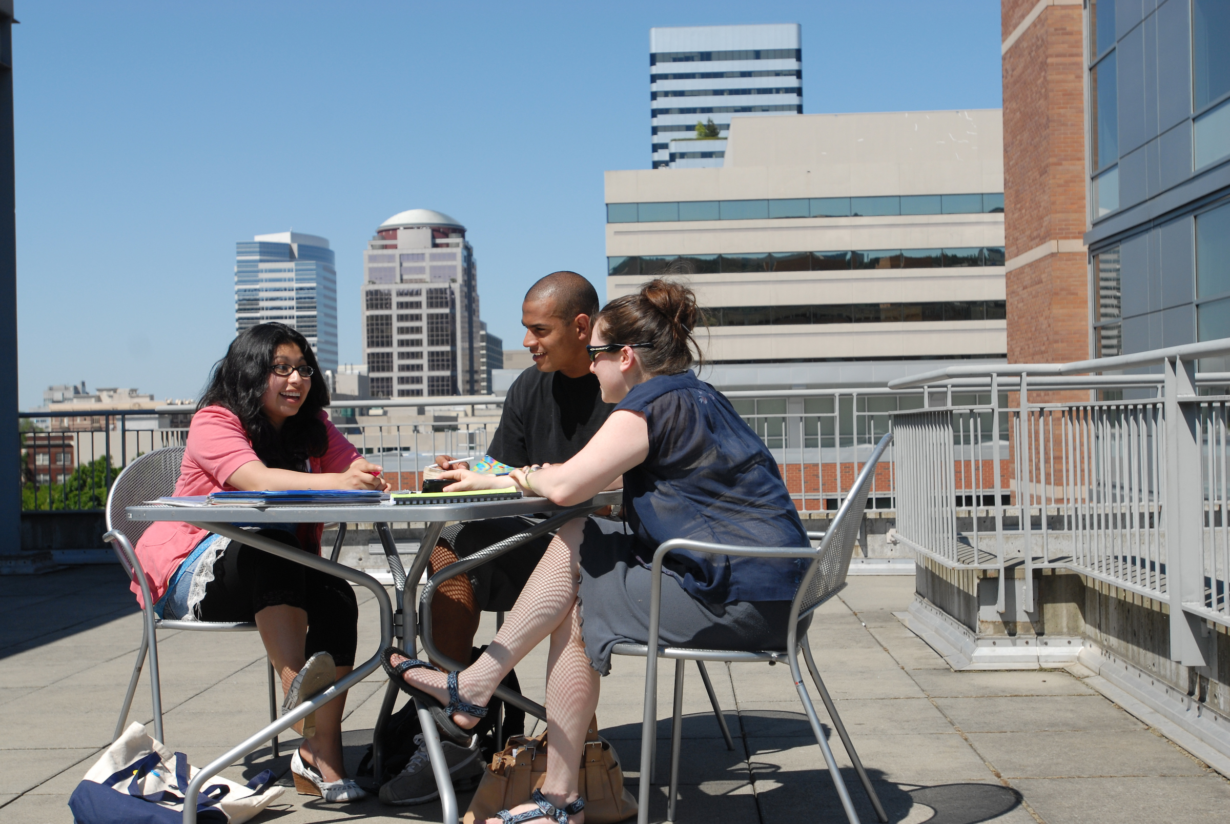 Group of three people talking at table on rooftop