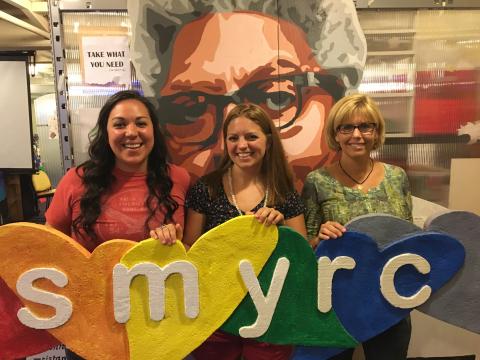 Image of Beth and Katie holding SMYRC sign