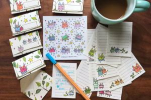 Owl stationary set of papers with little owls on them, stickers and labels next to a pen and a coffee mug.