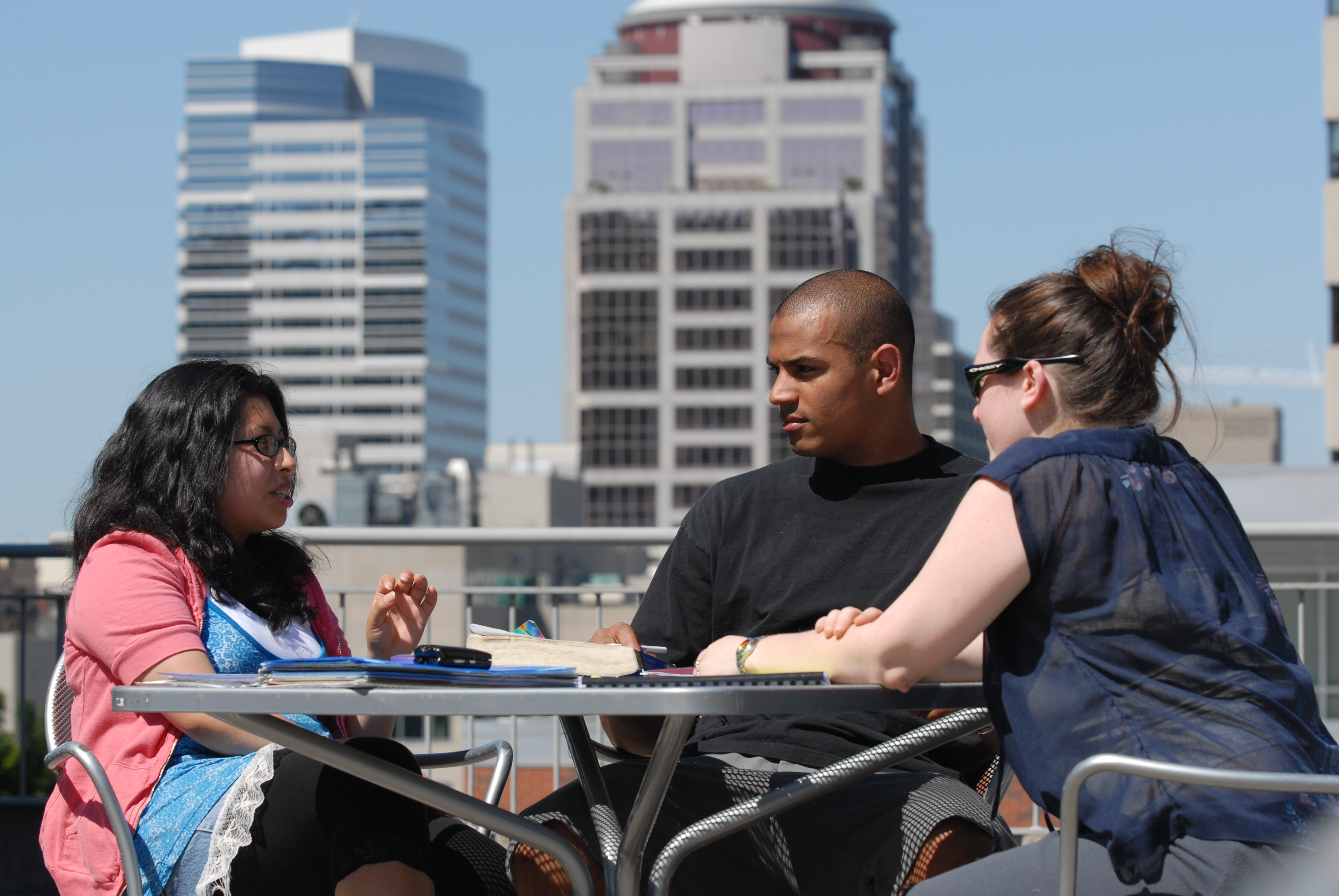 three individuals seated at an outside table